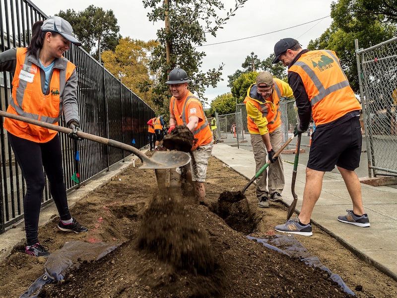 people in orange vests with shovels digging in dirt