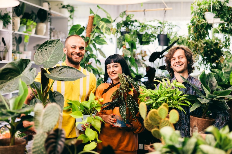 three people huddled around plants