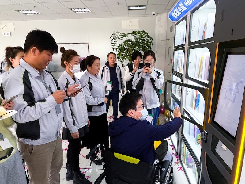 employees gathered around smart library vending machine